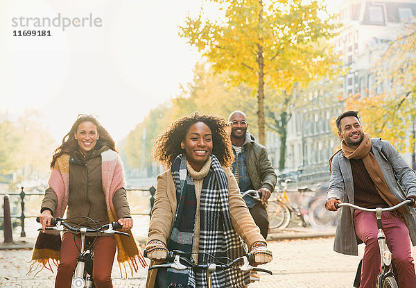 Lächelnde junge Freunde beim Radfahren auf der urbanen Herbststraße