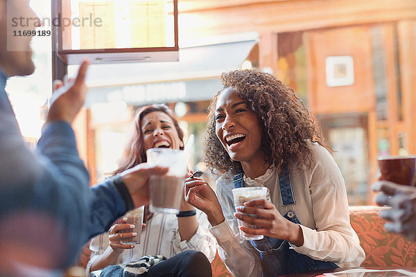 Lachende junge Freunde trinken Milchshakes im Cafe