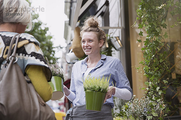 Florist zeigt einer Kundin im Laden Pflanzen