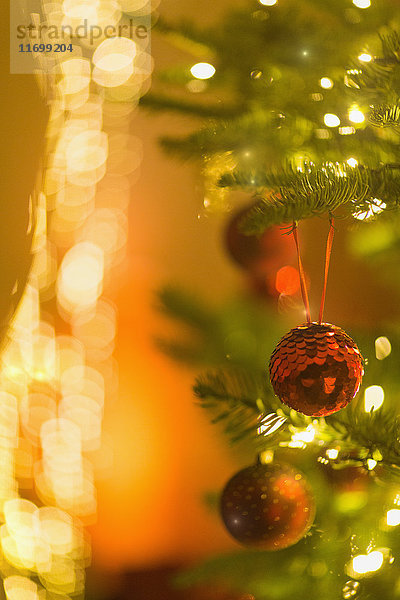 Roter Glitzerschmuck am Weihnachtsbaum mit Lichterkette