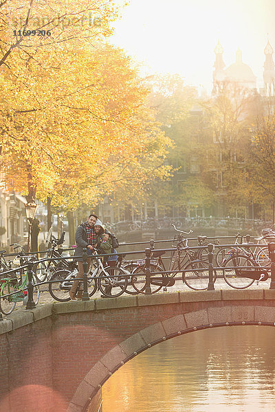 Portraitpaar mit Fahrrädern auf städtischer Herbstbrücke über den Kanal  Amsterdam