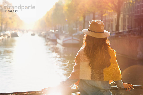 Frau mit Blick auf den sonnigen Herbstkanal  Amsterdam