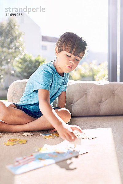 Fokussierter Junge montiert Puzzle auf Sofa