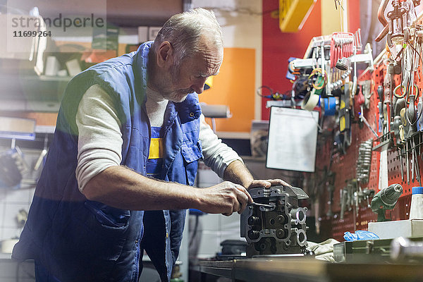 Senior Motorradmonteur  der Motorteil in der Werkstatt repariert
