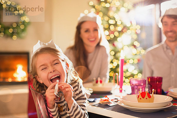 Porträt verspieltes Mädchen in Papier Krone Blasen Party Gunst an Weihnachten Abendessen Tabelle