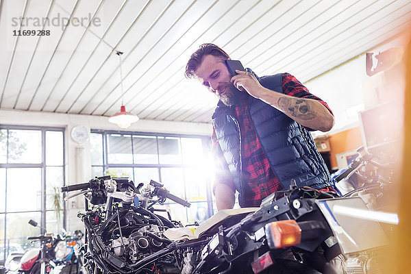Motorradmechaniker beim Telefonieren in der Werkstatt