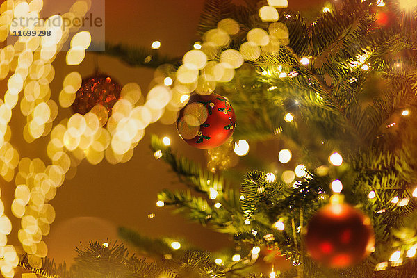 Rote Ornamente hängen am Weihnachtsbaum mit Lichterkette