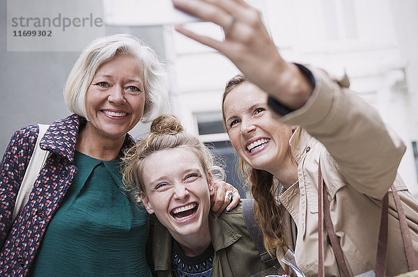 Lachende Mutter und Töchter machen ein Selfie