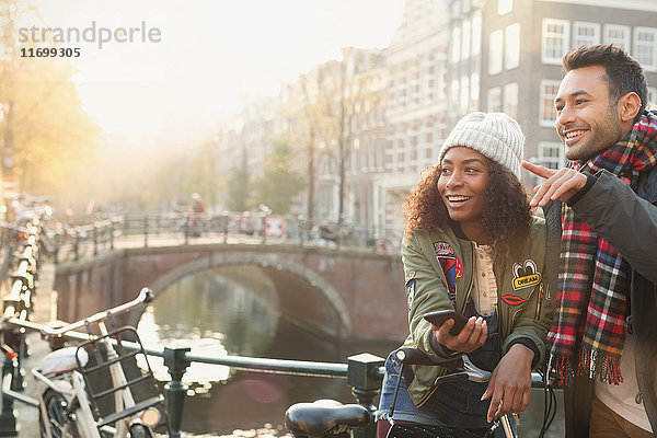 Junges Paar mit Fahrrädern auf der Stadtbrücke über den Kanal  Amsterdam