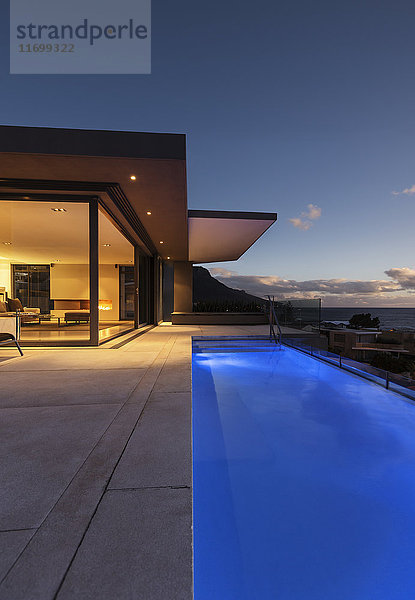 Blaue Schoßschwimmbad außerhalb des modernen luxuriösen Hauses Schaukastenaußenseite bei Nacht