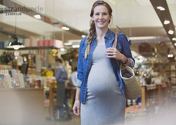 Porträt lächelnd schwangere Frau zu Fuß in Geschäft