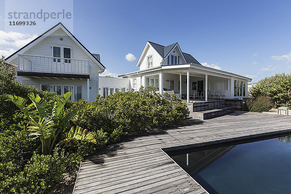 Sonniges  weißes  modernes Haus mit Außenbereich hinter dem Schwimmbad