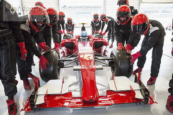 Boxencrew schiebt Formel-1-Rennwagen in die Reparaturwerkstatt