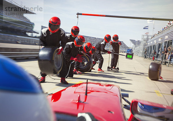 Boxencrew mit Reifen bereit für die Annäherung an Formel 1-Rennwagen in der Boxengasse