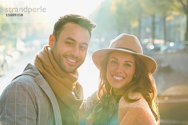 Portrait lächelndes junges Paar am sonnigen Herbstkanal
