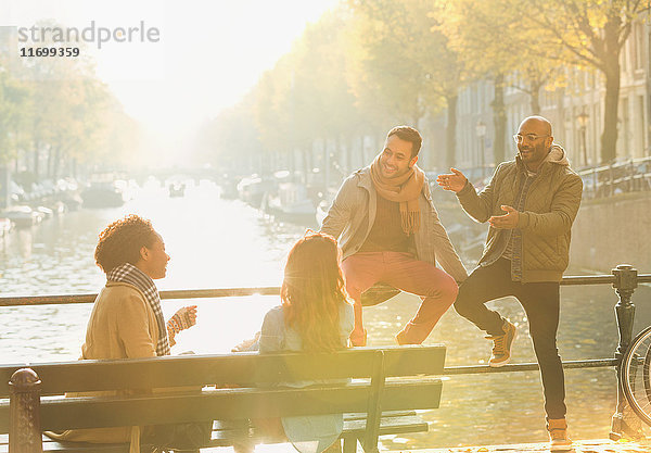 Junge Freunde beim Reden  auf der sonnigen städtischen Herbstbrücke über den Kanal  Amsterdam
