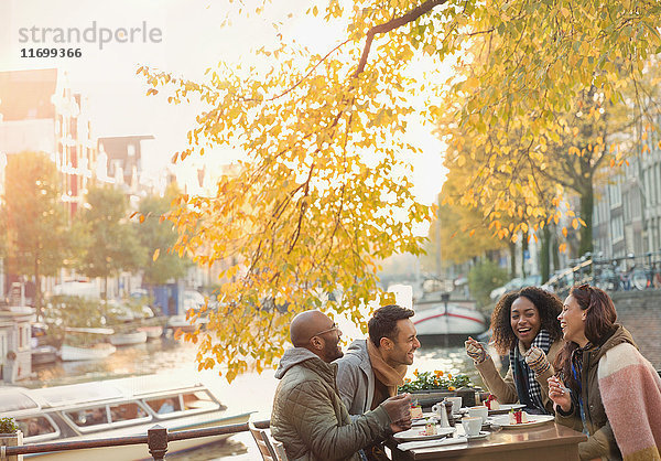 Freunde lachen und essen Käsekuchen Dessert im Herbst Bürgersteig Cafe entlang des Kanals  Amsterdam