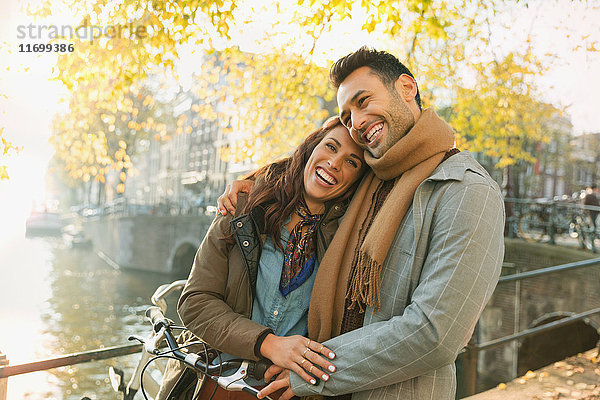 Lachendes junges Paar auf der Herbstbrücke über den Kanal in Amsterdam