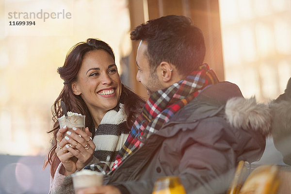 Lächelndes junges Paar trinkt Milchshakes im Straßencafé