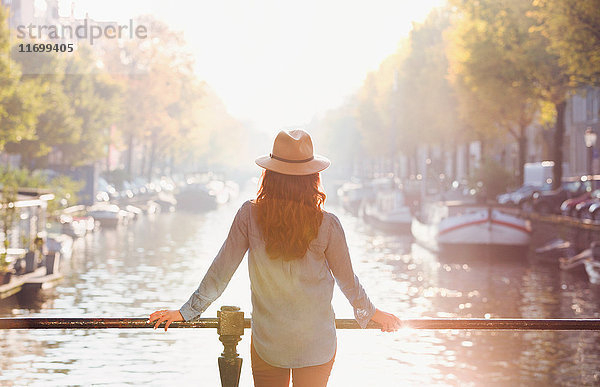 Frau mit Hut mit Blick auf den sonnigen Herbstkanal  Amsterdam