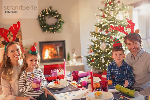 Porträt lächelnd junge Familie tragen Kostüm Rentiergeweih an Weihnachten Abendessen Tabelle