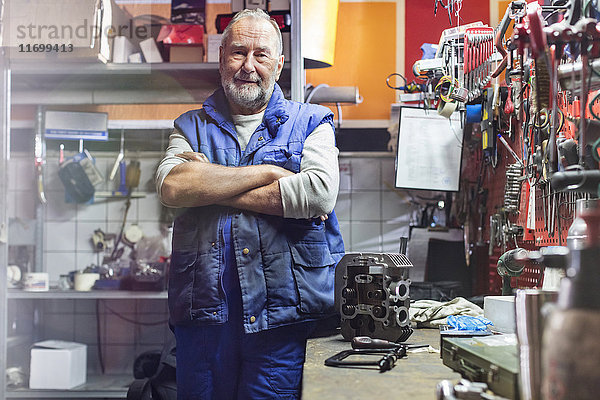 Porträt souveräner Senior-Motorradmechaniker in der Werkstatt