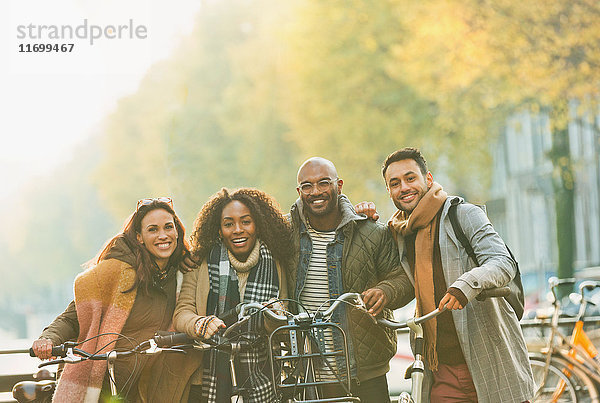 Portrait lächelnde Freunde Fahrrad fahren auf städtischer Herbststraße