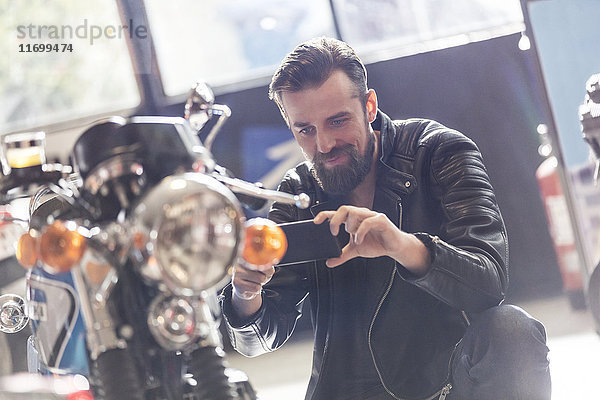 Mann mit Fotohandy fotografiert Motorrad im Geschäft