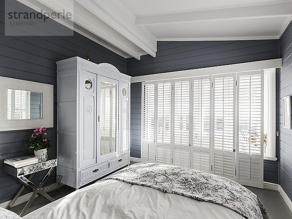 Luxuriöses Musterschlafzimmer mit weißen Fensterläden und Gewölbedecke