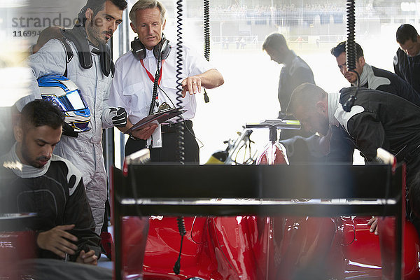 Manager und Formel-1-Fahrer bei der Arbeit am Rennwagen in der Reparaturwerkstatt