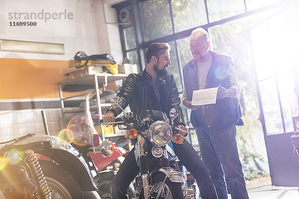 Motorradmechaniker und Kundengespräch in der Werkstatt