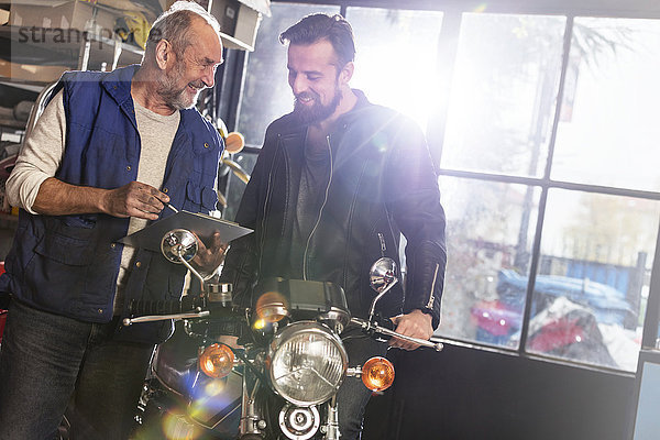 Motorradmechaniker im Gespräch mit dem Kunden in der Werkstatt