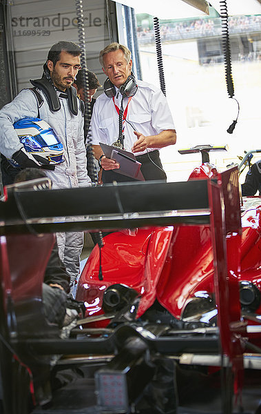 Manager und Formel-1-Rennfahrer im Gespräch in der Werkstatt