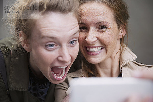 Verspielte  lachende Freundinnen  die ein Selfie mit einem Fotohandy machen