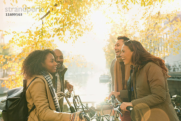 Junge Freunde mit Fahrrädern entlang des sonnigen Herbstkanals
