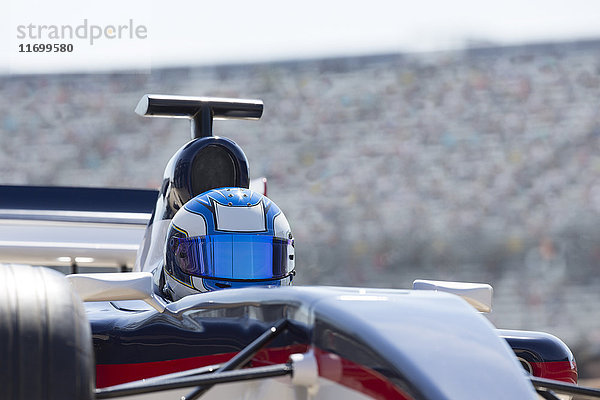 Formel-1-Rennwagenfahrer mit Helm auf der Rennstrecke