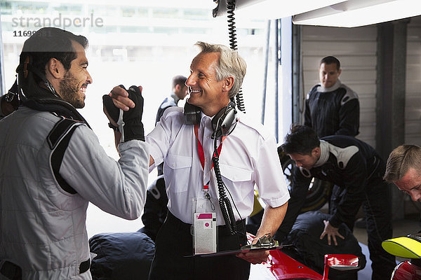 Manager und Formel-1-Fahrer feiern  Händeschütteln in der Werkstatt