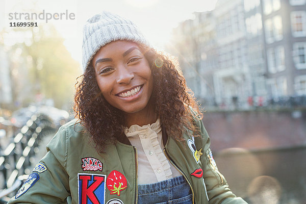 Portrait lächelnde junge Frau auf sonniger urbaner Herbststraße