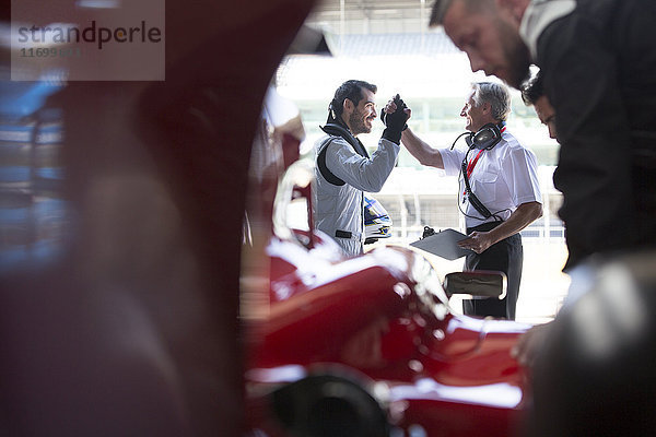 Manager und Formel-1-Rennwagenfahrer in der Reparaturwerkstatt