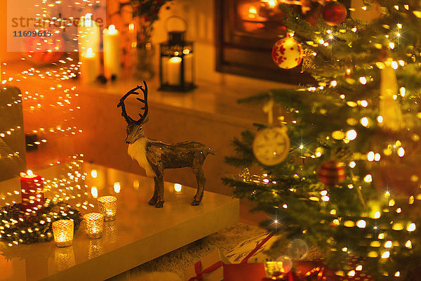 Rentierdekoration im stimmungsvollen Wohnzimmer mit Kerzen und Weihnachtsbaum