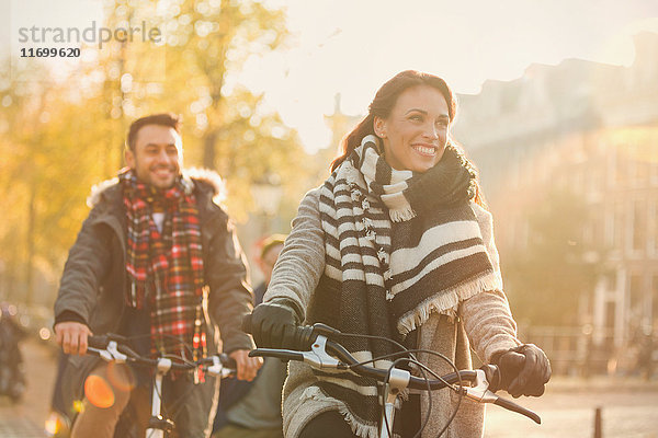 Lächelndes junges Paar beim Radfahren auf der urbanen Herbststraße