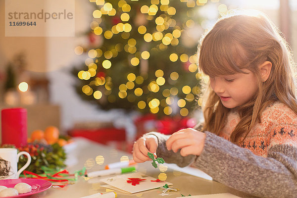 Mädchen bastelt Weihnachtsschmuck am Tisch