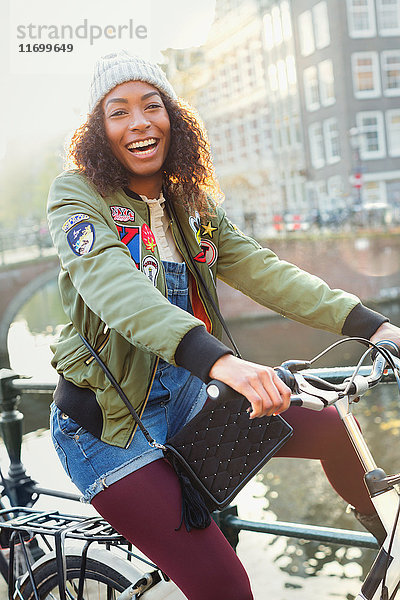 Portrait verspielte junge Frau Fahrrad fahren entlang des Stadtkanals