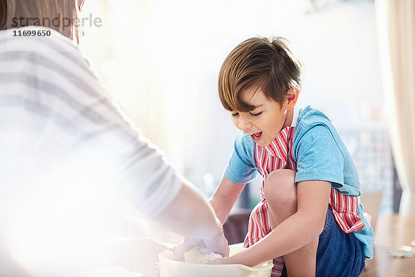 Lächelnder Junge hilft Mutter beim Backen  Teig mischen in der Schüssel