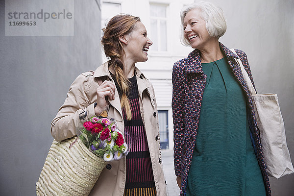 Lächelnde Mutter und Tochter mit Einkaufstüten in einer Gasse