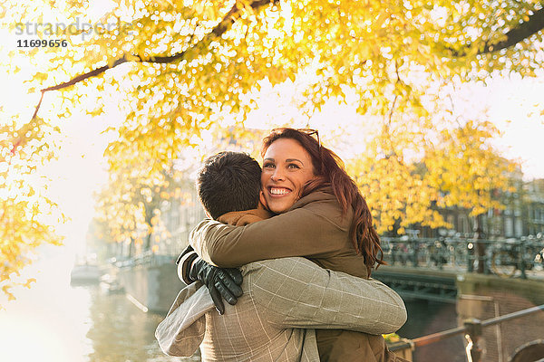 Glückliches Paar am sonnigen städtischen Herbstkanal  Amsterdam
