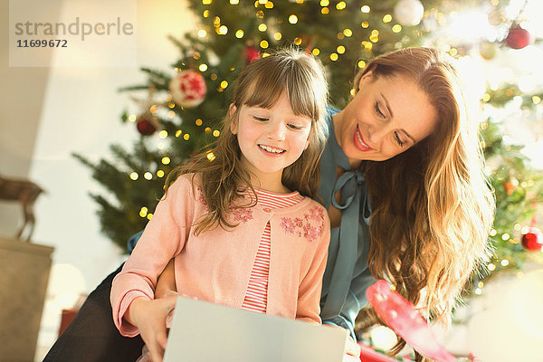 Mutter beobachtet Tochter beim Öffnen des Weihnachtsgeschenks