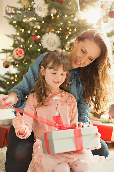 Mutter hilft Tochter beim Öffnen des Weihnachtsgeschenks