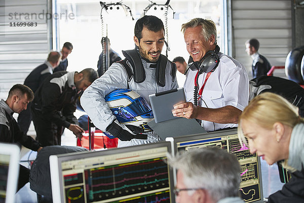 Manager und Formel-1-Fahrer mit digitalem Tablett in der Reparaturwerkstatt