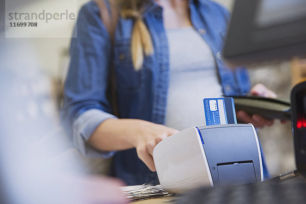 Weibliche Kundin benutzt ein Kreditkartenlesegerät in einem Geschäft